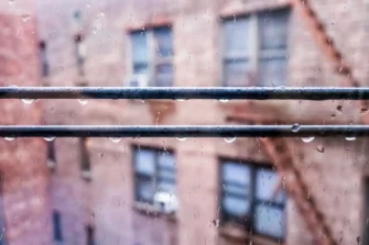 Rain falling outside a New York City residential building during storm season