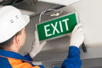Worker installing exit sign for Clearing HPD Violations post.
